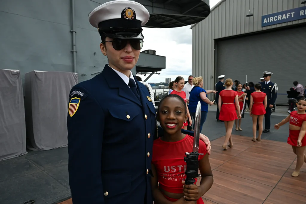 U.S. Coast Guard Seaman Niki Reyna, a member of the U.S. Coast Guard Ceremonial Honor Guard Silent Drill Team, poses for a photo with United States Tournament of Dance team members