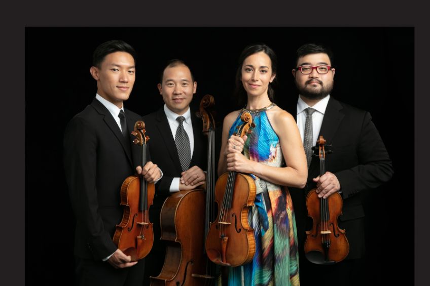 Three men and one woman in their 30's holding their string instruments